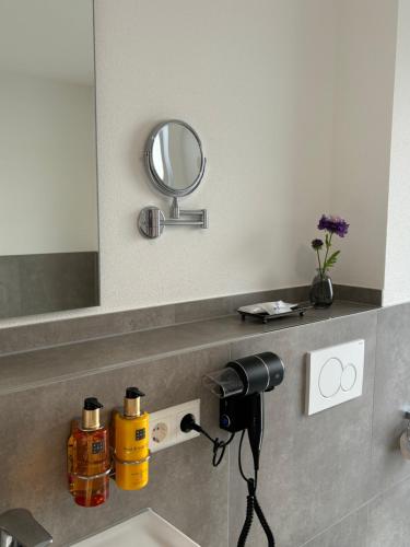 a bathroom sink with a camera and a mirror at REMA Homes - Luxuriöse Apartments - Messenähe - Offenburg in Offenburg