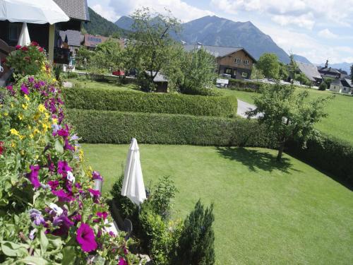 a garden with a white umbrella and some flowers at Abis Ferienwohnung Salzkammergut in Strobl