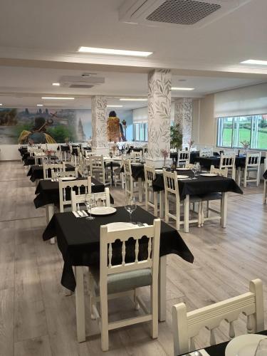 a dining room with tables and white chairs at Pensión A Codeseira Melide in Melide