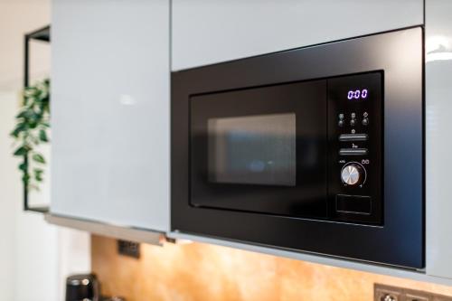 a microwave oven hanging on a wall in a kitchen at Terrace View Apartment - Golden Apartments Rezidence Nová Karolina in Moravská Ostrava