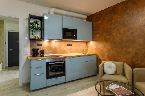 a kitchen with blue cabinets and a living room at Terrace View Apartment - Golden Apartments Rezidence Nová Karolina in Moravská Ostrava