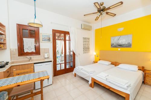 a bedroom with two beds and a kitchen with yellow walls at Aegina Town Cozy Escape in Aegina Town