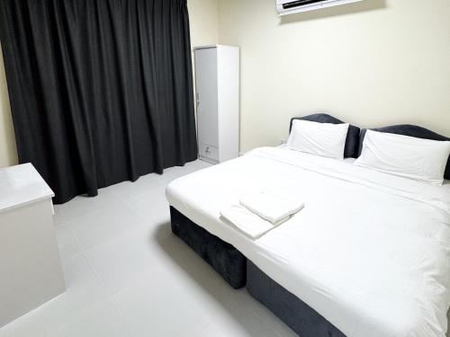 a bedroom with a large white bed with black curtains at Twar Star Residence in Dubai