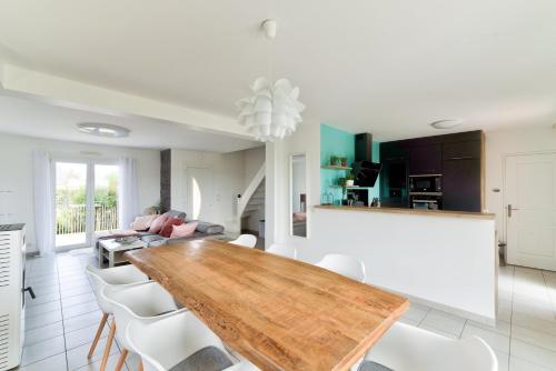 une salle à manger avec une table en bois et des chaises blanches dans l'établissement Maison Flair, à Varaville