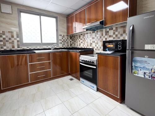 a kitchen with wooden cabinets and a refrigerator at Twar Star Residence in Dubai