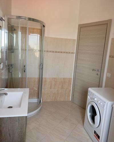 a bathroom with a shower and a sink and a washing machine at Appartamenti Estivi in Cirò Marina