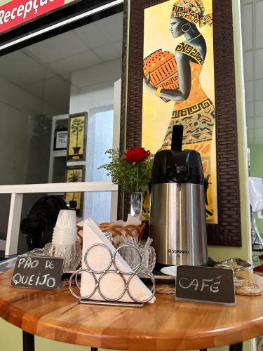 a table with a coffee maker and signs on it at Hotel Netto in Cachoeiras de Macacu