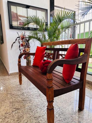 a wooden bench with red pillows in a room at Hotel Netto in Cachoeiras de Macacu