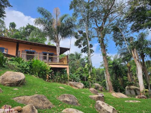ein Haus auf einem Hügel mit Felsen davor in der Unterkunft Bangalô com vista e piscina natural em Flechas in Ilhabela
