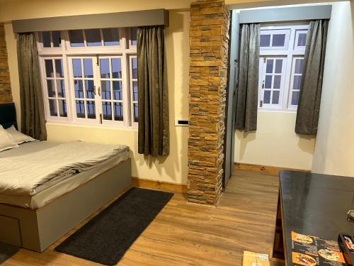 a bedroom with a bed and two windows at Norbu Thungkar Homestay in Darjeeling