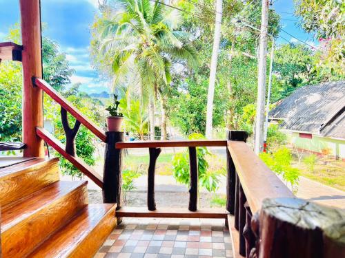 a wooden staircase leading to a porch with palm trees at ลูกดกแน่โฮมสเตย์ ที่พักเกาะลิบง in Ko Libong