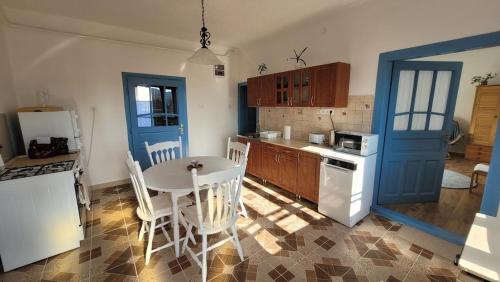 a kitchen with a table and a blue door at Kék Rigó Dézsafürdős Vendégház in Mátranovák
