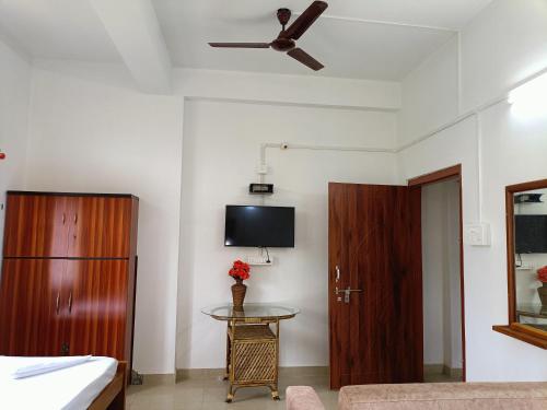 a room with a bed and a tv and a table at Blueberry Homestay in Guwahati