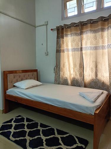 a bedroom with a bed with a curtain and a rug at Blueberry Homestay in Guwahati