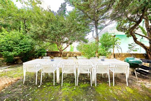une table blanche et des chaises assises sous un arbre dans l'établissement Jt Tailored Service Home Near Hyehwa Station, à Séoul
