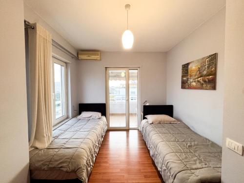 due letti in una stanza con due finestre di Cozy Apartment Near the Pyramid, Tirana Center a Tirana