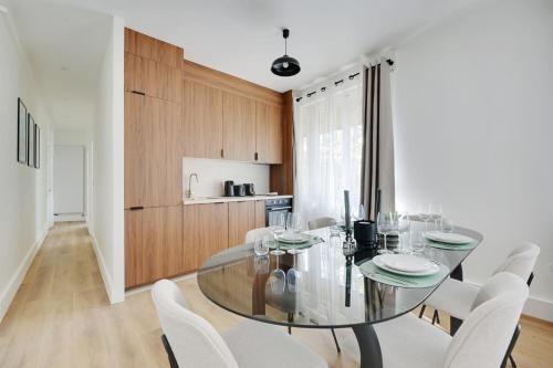 une salle à manger avec une table en verre et des chaises blanches dans l'établissement Beautiful apartment 8pers, à Paris