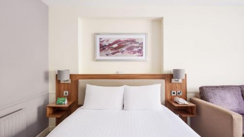 a hotel room with a bed and a chair at Holiday Inn Taunton M5, Jct25 by IHG in Taunton