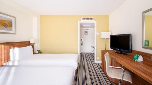 a hotel room with two beds and a flat screen tv at Holiday Inn Taunton M5, Jct25 by IHG in Taunton