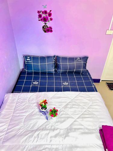 two flowers in vases on a bed with purple walls at ลูกดกแน่โฮมสเตย์ ที่พักเกาะลิบง in Ko Libong