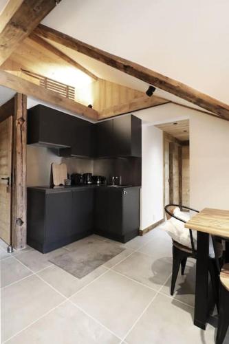 une cuisine avec des murs noirs, une table, une table et des chaises dans l'établissement Logement de vacances exclusif - Plein centre, à Arâches-la-Frasse
