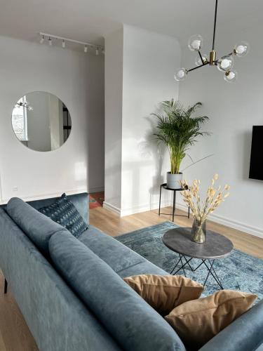 a living room with a blue couch and a mirror at Šiauliai CENTER Višinskio NEW self check In in Šiauliai