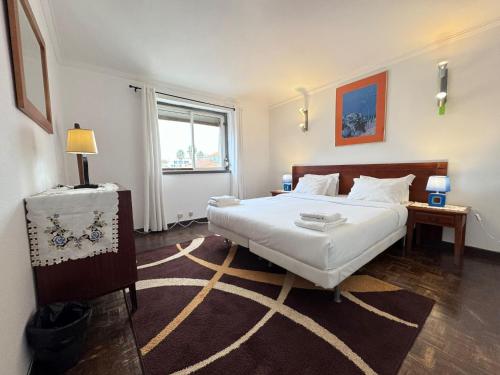 a bedroom with a large white bed and a window at The Pearl - Cascais Guest House - City & Beach in Cascais
