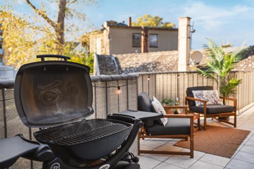 a grill on a balcony with chairs and a house at EDLER WOHNRAUM Schwanenteich-Suite mit Balkon, Kaffeevollautomat, Lift & Parkplatz in Zwickau