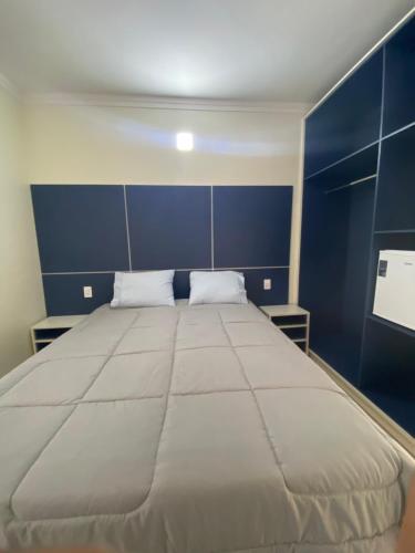 a large bed in a room with a blue wall at Trembão Hotel & Suítes in Ribas do Rio Pardo