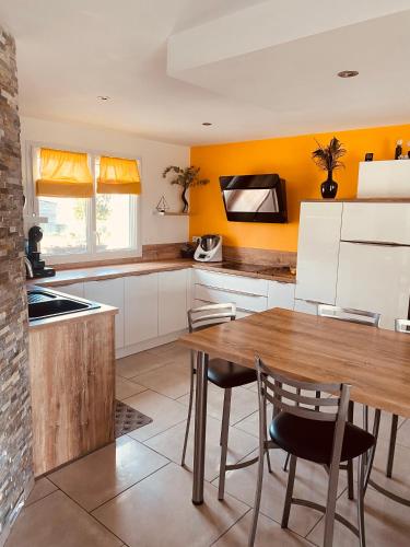 une cuisine avec une table en bois et des murs jaunes dans l'établissement Chambre terracotta, à Orgères