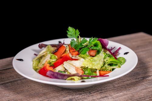 a white plate with a salad on a table at Pension Tibor a Luna in Cerny Dul