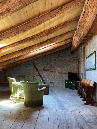 a living room with wooden ceilings and green chairs at Casa nel centro storico di Borno in Borno