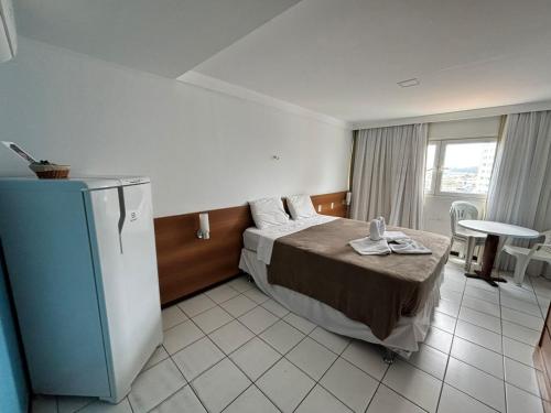 a hotel room with a bed and a refrigerator at Flat Praia de PontaNegra - Natal RN in Natal