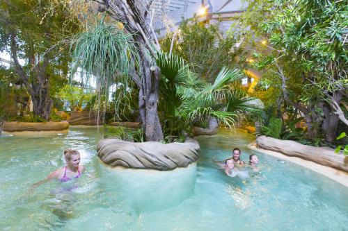 3 personnes se baignant dans une piscine dans un jardin dans l'établissement Chalet Sapin by Avoriaz Chalets, à Avoriaz