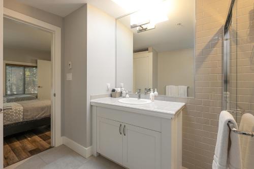a white bathroom with a sink and a mirror at Pacific Forest Beach House in Parksville