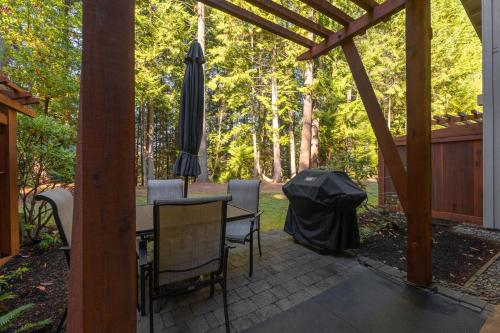 a patio with an umbrella and a table and chairs at Pacific Forest Beach House in Parksville