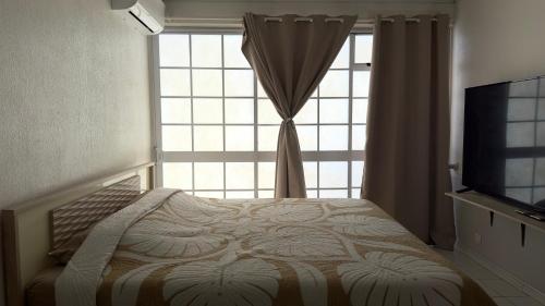 a bedroom with a window with a bed and a television at Vaiata lodge in Arue