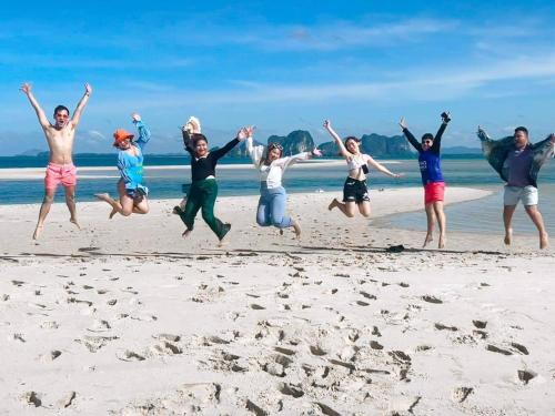 a group of people jumping on the beach at ลูกดกแน่โฮมสเตย์ ที่พักเกาะลิบง in Ko Libong