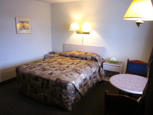 a hotel room with a bed and a table at Chinook Motel in Lethbridge