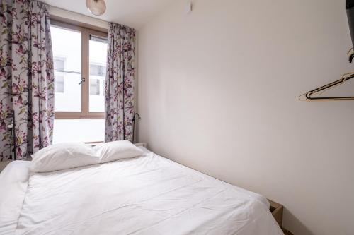 a white bed in a room with a window at De Moriaan Historic Center in Antwerp