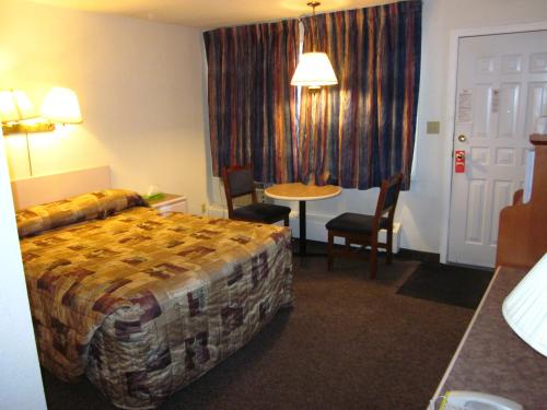 a hotel room with a bed and a table and chairs at Chinook Motel in Lethbridge