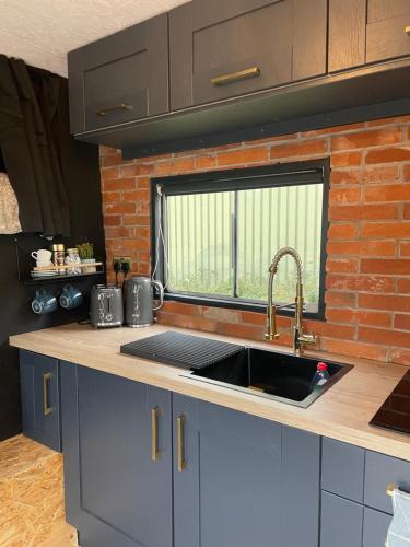 a kitchen with a sink and a brick wall at Horse Truck Tiny Home with Hot Tub in Ashbourne