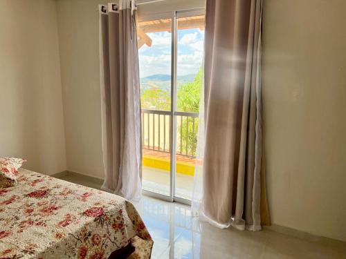 Un dormitorio con una cama y una ventana grande. en Chácara Aconchego da Serra, en Serra Negra