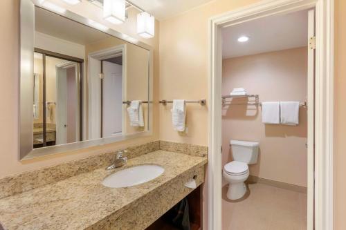 a bathroom with a sink and a toilet and a mirror at Best Western Plus West Covina Inn in West Covina