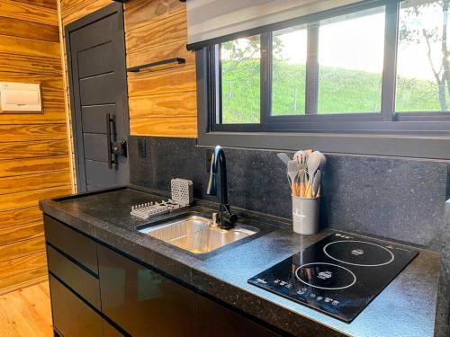 a kitchen with a sink and a counter top at Vivenda das Araucárias 02 Microcasa Aconchegante lareira, banheira in Rio Rufino