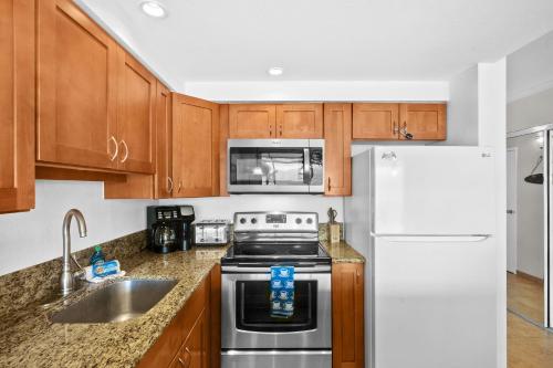 a kitchen with wooden cabinets and a white refrigerator at Maalaea Kai 311 - Direct Ocean Front, Split AC in Wailuku