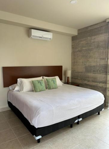 カンクンにあるNew Centric 1BR apartment with gym & poolの緑の枕が付いた大きな白いベッドのある寝室