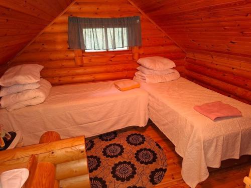 a bedroom with two beds in a log cabin at Rantarinne 543 B in Kuusamo