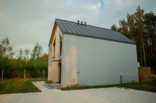 a large white building with a black roof at Lasownia Dom Dzięcioł in Wielęcin