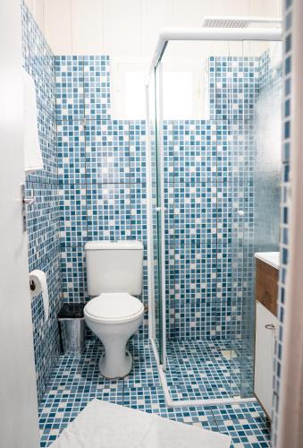 a blue tiled bathroom with a toilet and a shower at Granbalaio Hostel in Blumenau